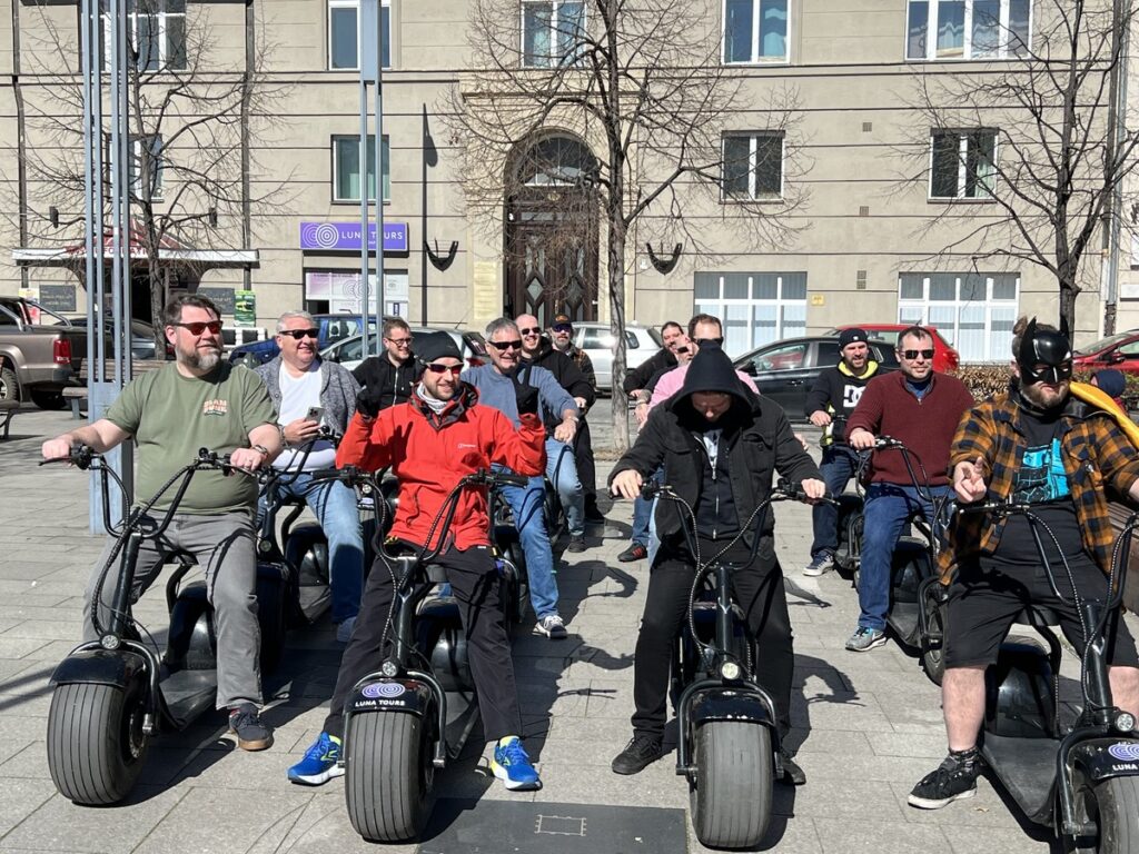 A group of men riding e-scooters, enjoying a sunny day and exploring the city together