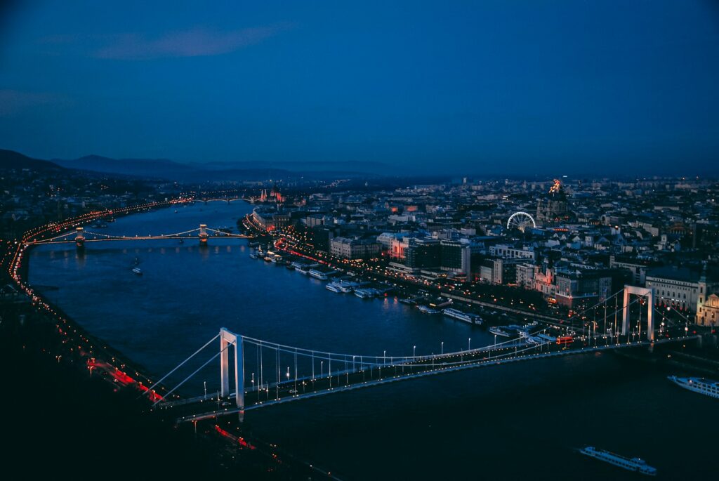 A stunning nighttime view of Budapest, featuring the Danube River, illuminated bridges, and city lights.