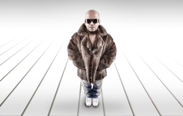 Man dressed in a fur coat and sunglasses standing confidently, representing the unique dwarf handcuff Budapest stag do experience.