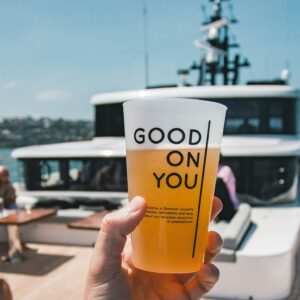 Hand holding a beer cup on a sunny boat deck, capturing the fun and relaxed vibes of a beer cruise Budapest stag activity.
