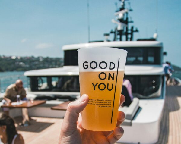 Hand holding a beer cup on a sunny boat deck, capturing the fun and relaxed vibes of a beer cruise Budapest stag activity.
