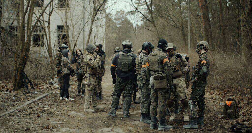 A group of people in camouflage and gear are gathered outdoors for a paintball game, making it a fun and action-packed stag do activity.
