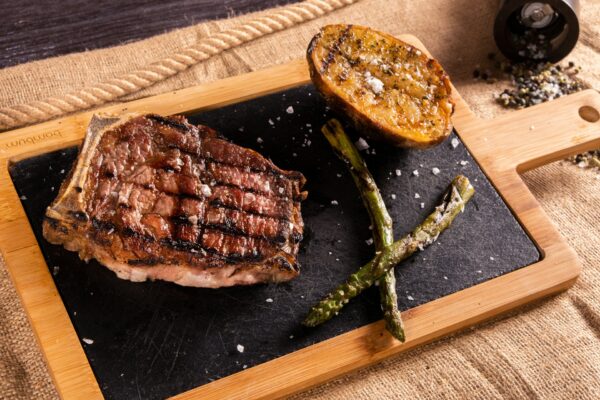 Juicy grilled steak served with roasted potato and asparagus, showcasing the delicious dining experience of strip dinner Budapest stag activities