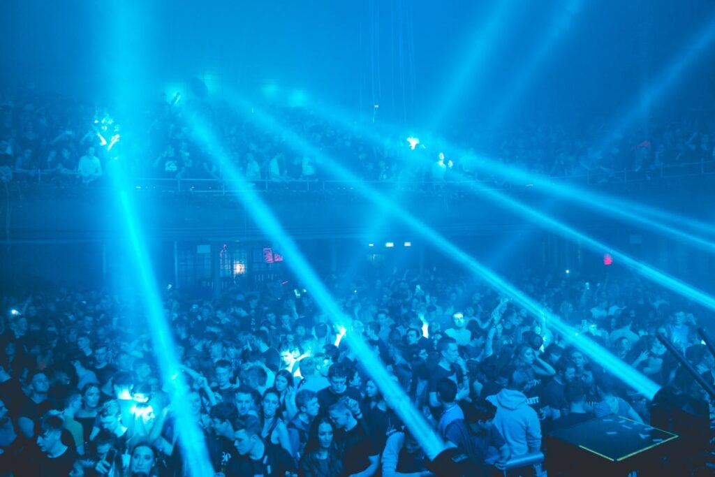 A packed nightclub with vibrant blue lights and a lively crowd, showcasing the energy of VIP clubbing experiences