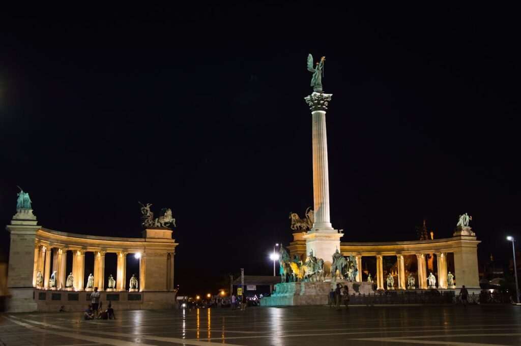 Heroes' Square in Budapest illuminated at night, showcasing its grand statues and historic significance
