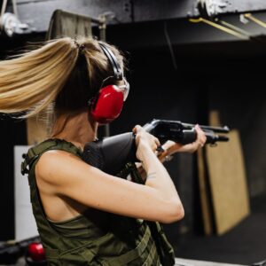 Woman aiming a shotgun at a shooting range, representing a thrilling gun shooting stag party in Budapest experience.