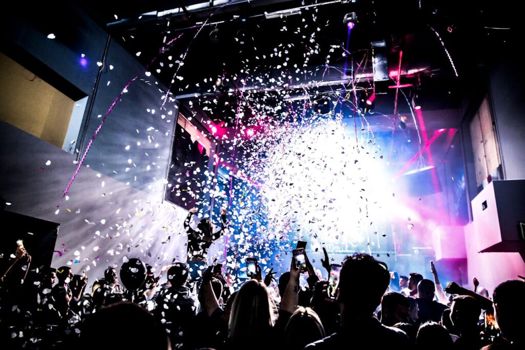 A vibrant nightclub scene with confetti raining down on a crowd celebrating under colorful lights.