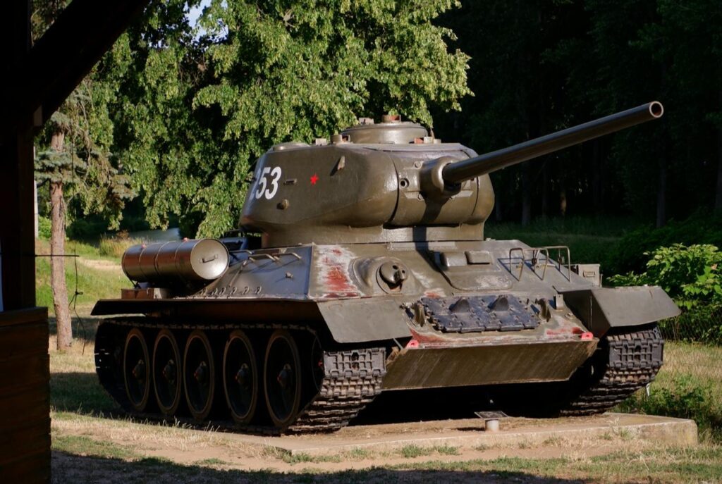 A vintage tank displayed outdoors surrounded by greenery, offering a glimpse of an adventurous experience