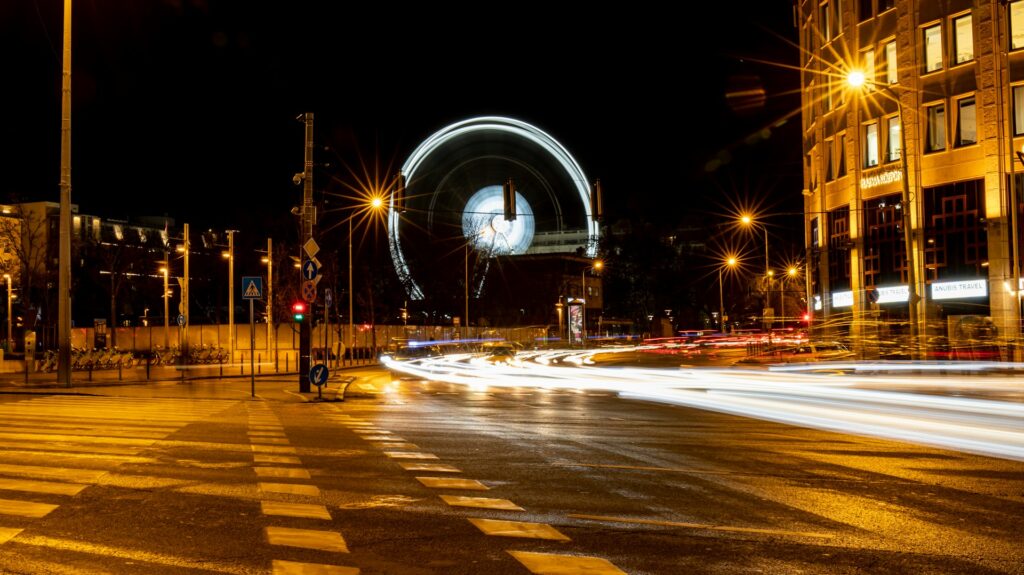 Night view of Budapest with a lit Ferris wheel and bustling streets, showcasing the vibrant nightlife near Budapest stag do accommodation