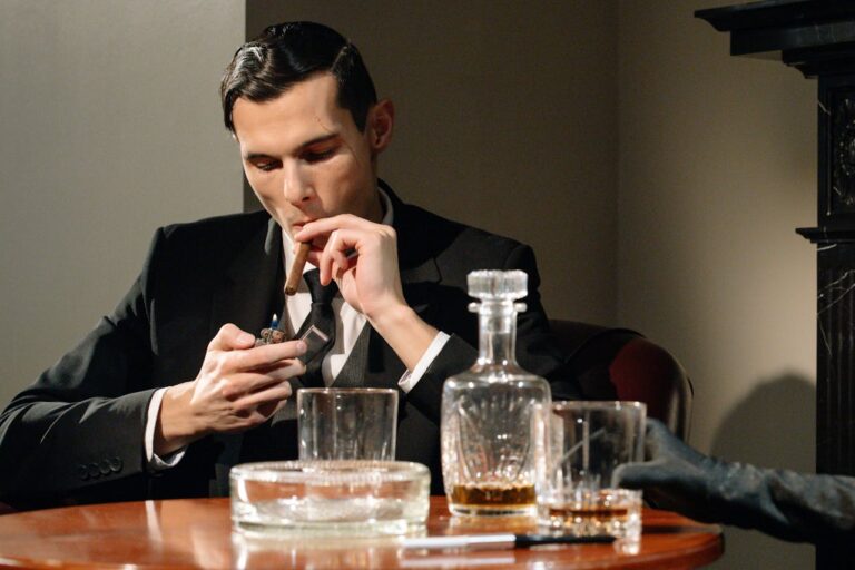 Man in a suit enjoying a cigar and whiskey, creating the perfect ambiance for celebrating and understanding how to plan a stag do.