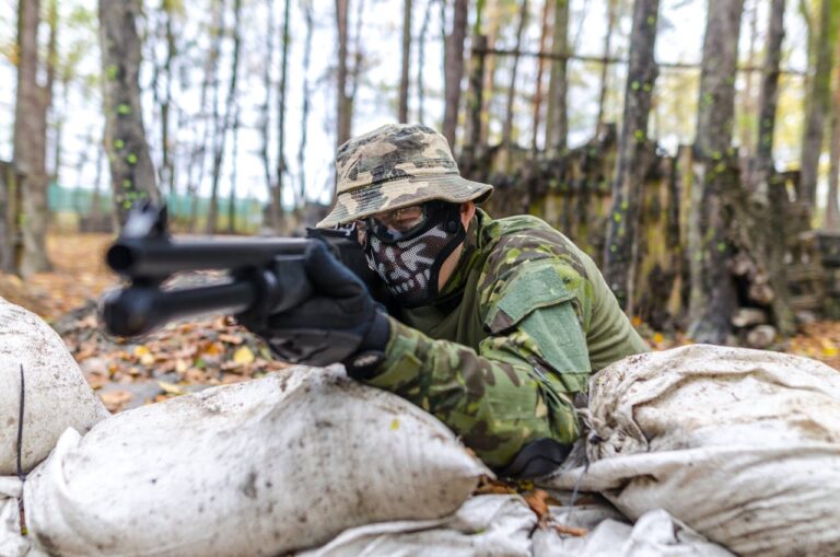 Thrilling outdoor experience with gun shooting packages Budapest, showcasing a participant in full gear aiming a firearm in a forest setting.